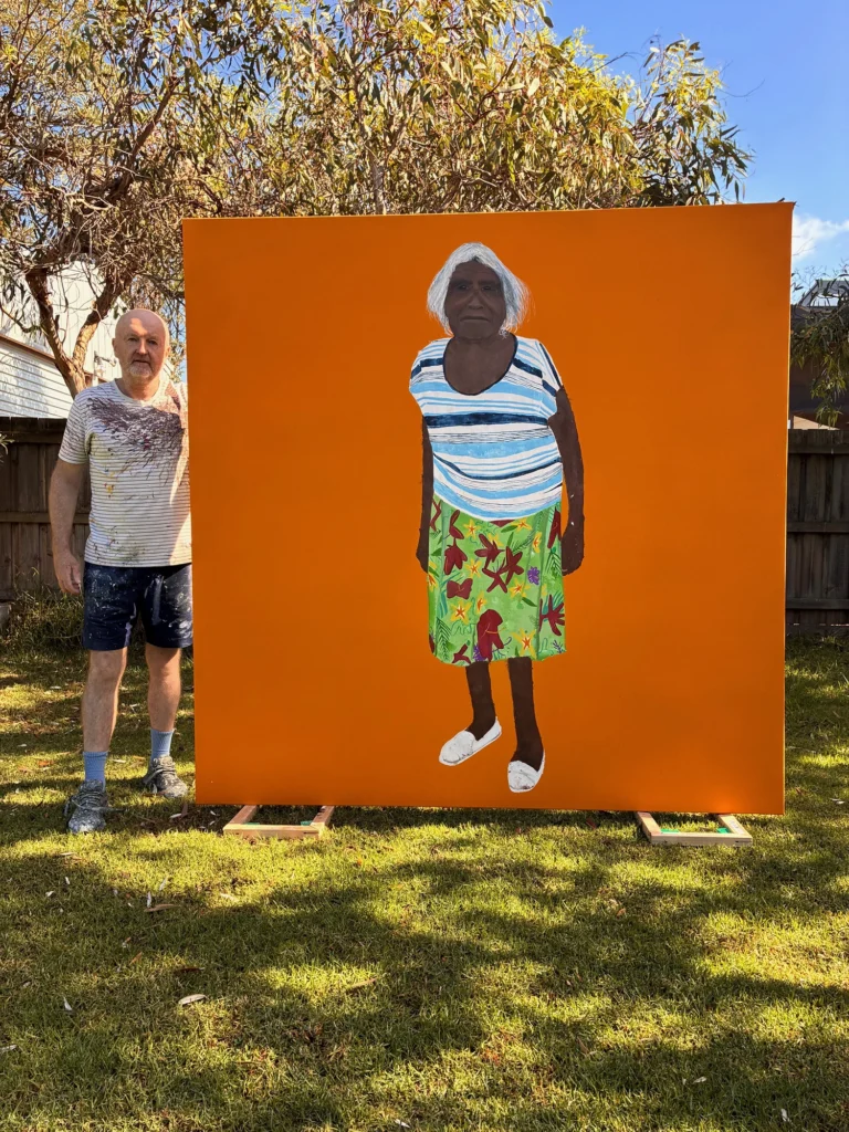 Image credit: Richard Lewer standing with his portrait of Iluwanti Ken. Photo courtesy of the artist